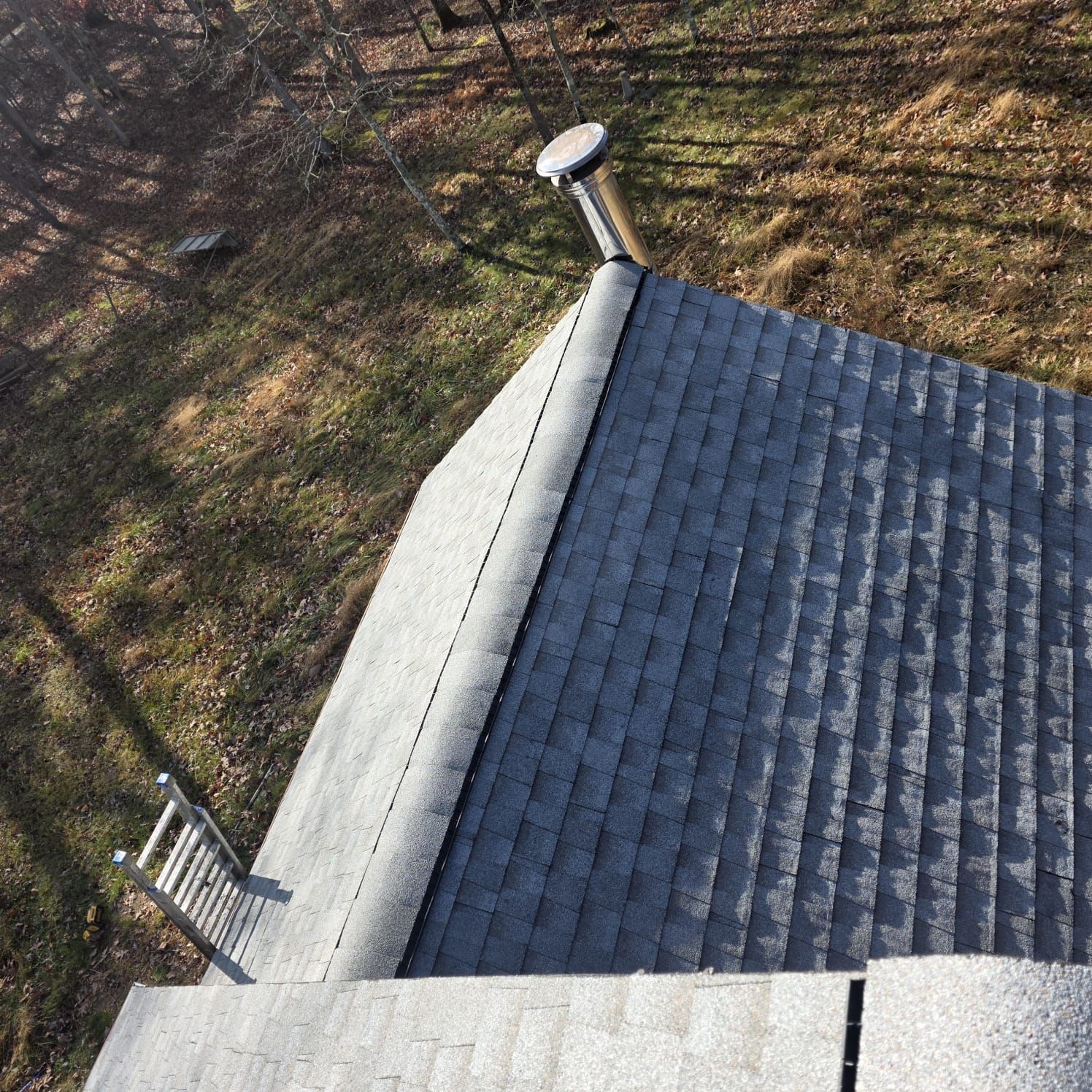 Overhead view of a gray asphalt shingle roof with a chimney and a small ladder.