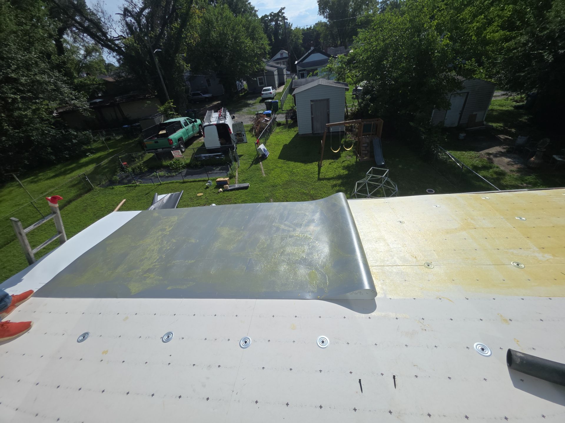 Rooftop worksite with workers, tools, and green trees in the background