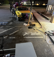 A yellow truck is being towed by a crane in a parking lot