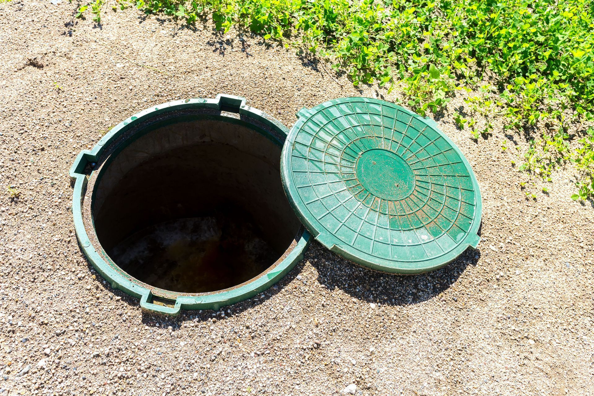 a green manhole cover is open to a hole in the ground