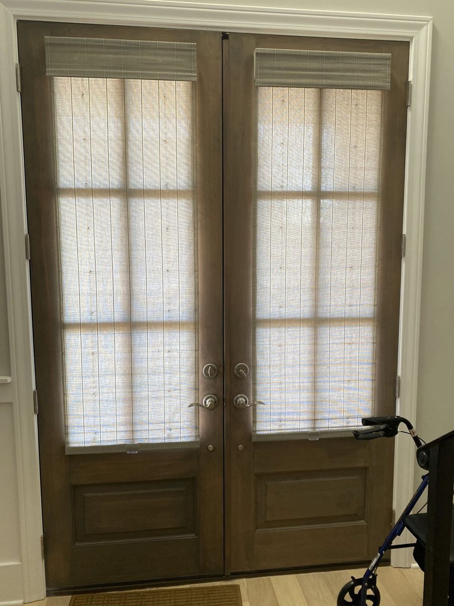 Two brown French doors with beige woven shades; a walker is in the right foreground.