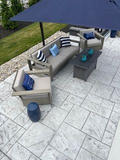 A patio with a couch , chairs , table and umbrella.