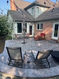 A patio with chairs and umbrellas in front of a house.