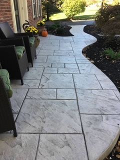 A patio with chairs and flowers on it in front of a house.