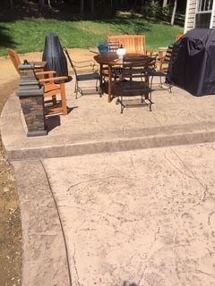 A patio with a table and chairs and a grill.