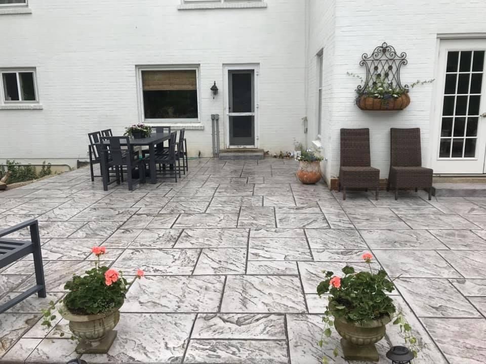 A patio with a table and chairs in front of a white house.