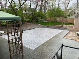 A patio with a gazebo and trees in the background.