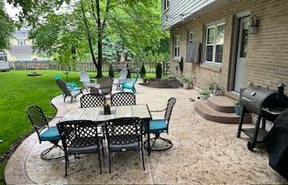 A patio with a table and chairs and a grill.