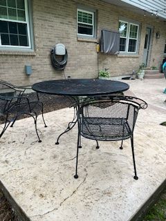 A table and chairs are sitting on a patio in front of a brick house.