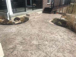 A concrete walkway leading to a porch of a house.