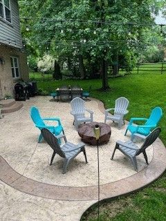 A group of chairs are sitting around a fire pit on a patio.