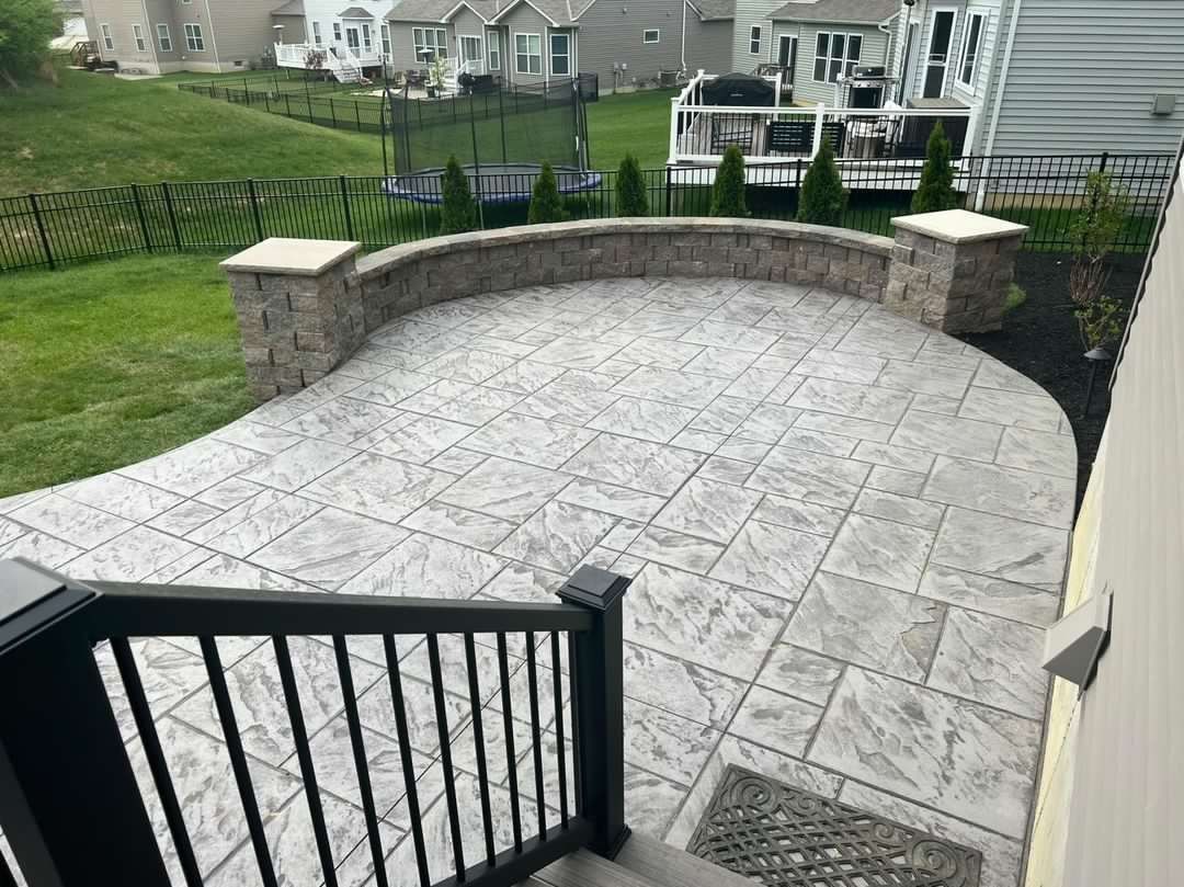 A patio with a black railing and a brick wall in the backyard of a house.