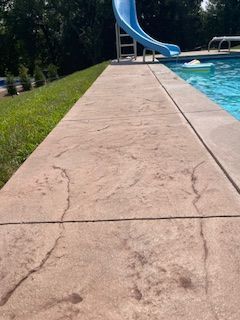A concrete walkway leading to a swimming pool with a slide.