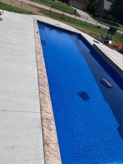A large blue swimming pool is sitting on top of a concrete patio.