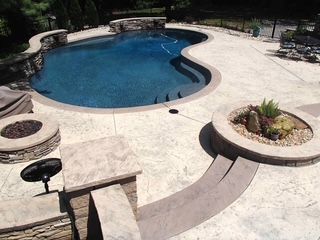 A large swimming pool with a fire pit in the middle