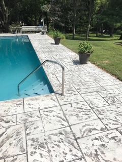 A swimming pool with a concrete walkway leading to it.