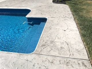 A swimming pool with a concrete deck next to it.