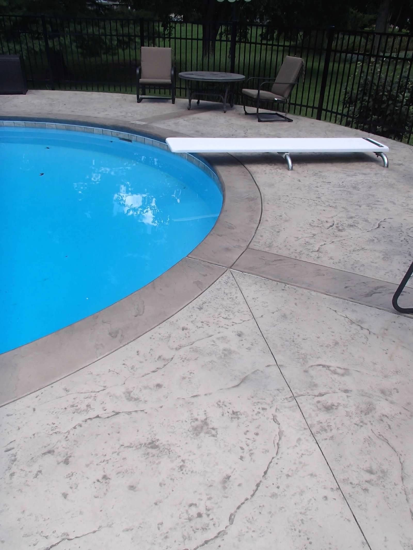 A swimming pool with chairs and a table around it