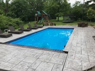A large swimming pool surrounded by chairs and a playground.