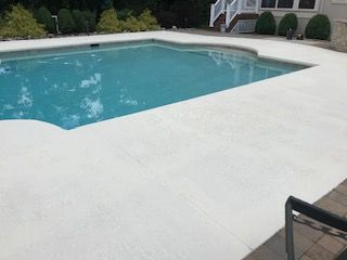 A large swimming pool surrounded by a white concrete deck.