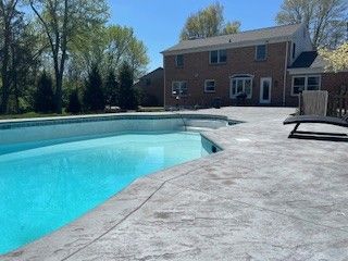 There is a large swimming pool in the backyard of a house.