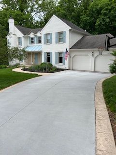 A large white house with a concrete driveway leading to it.