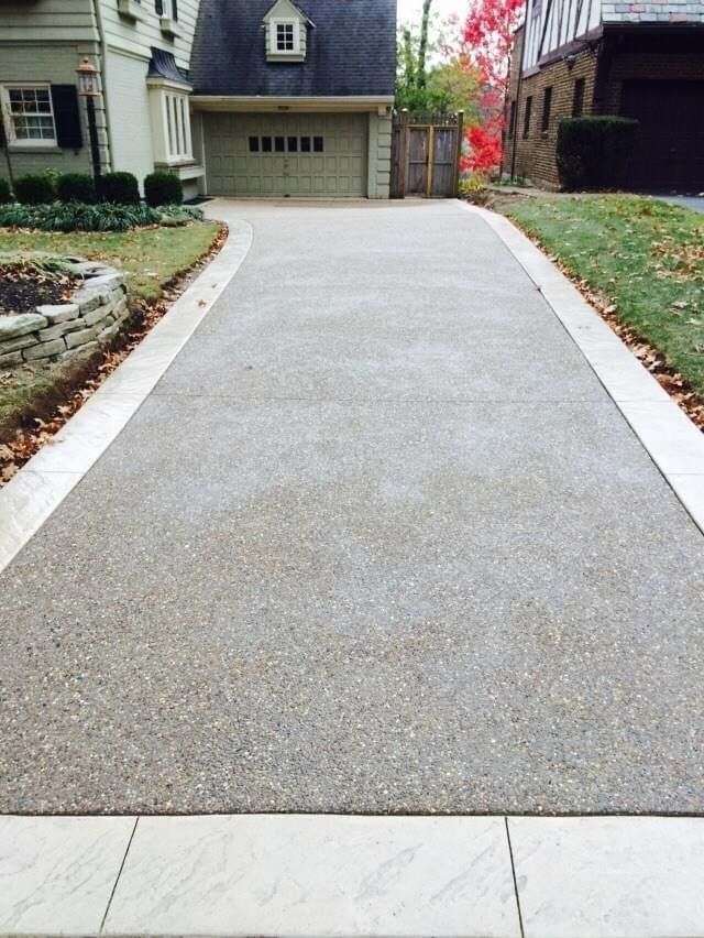 A concrete driveway leading to a house with a garage