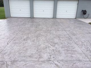 A concrete driveway with three garage doors in the background.