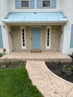 The front of a house with a blue door and a walkway leading to it.