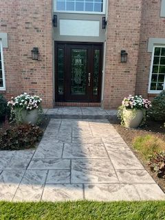 A brick house with a concrete walkway leading to the front door.