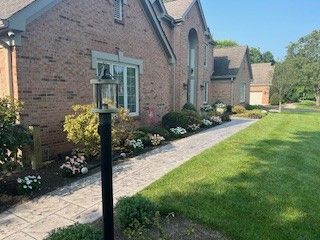 A brick house with a walkway leading to it and a lamp post in front of it.