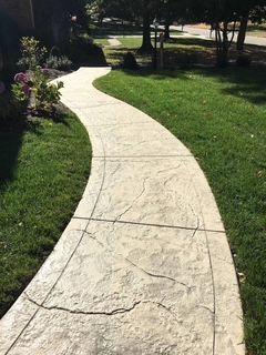 A concrete walkway going through a lush green field.
