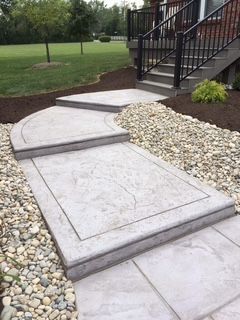 A concrete walkway with stairs leading up to a house.