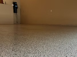 Empty carpeted room with beige walls and a wall-mounted device in the corner