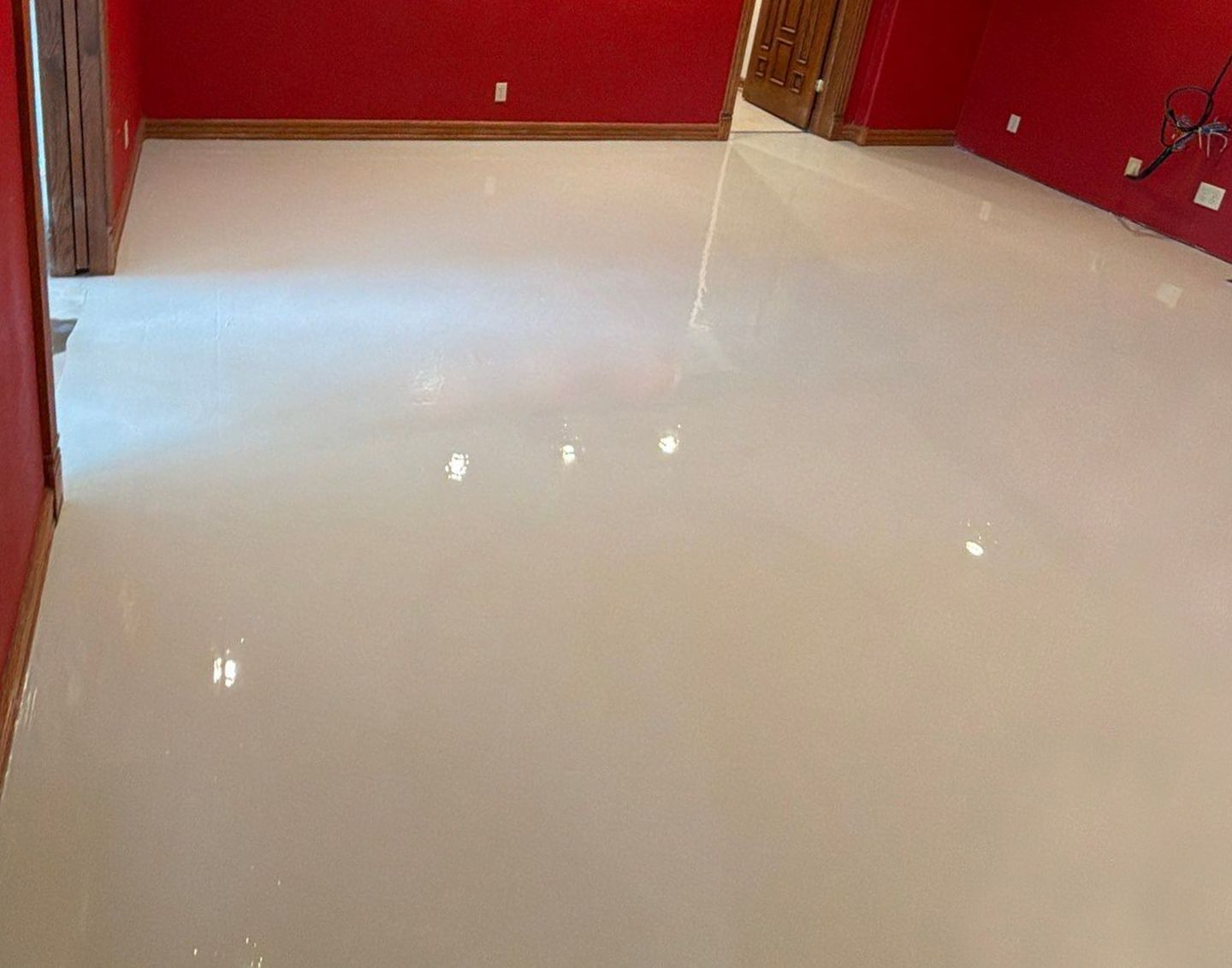 Glossy white floor in a red-walled room with open doorways and bright reflections.