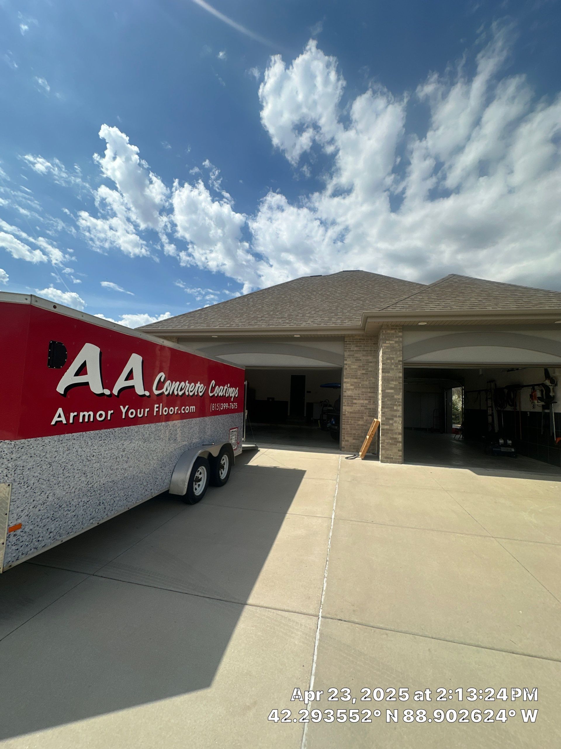 Red AAA moving truck parked in front of a suburban house under a bright sky.