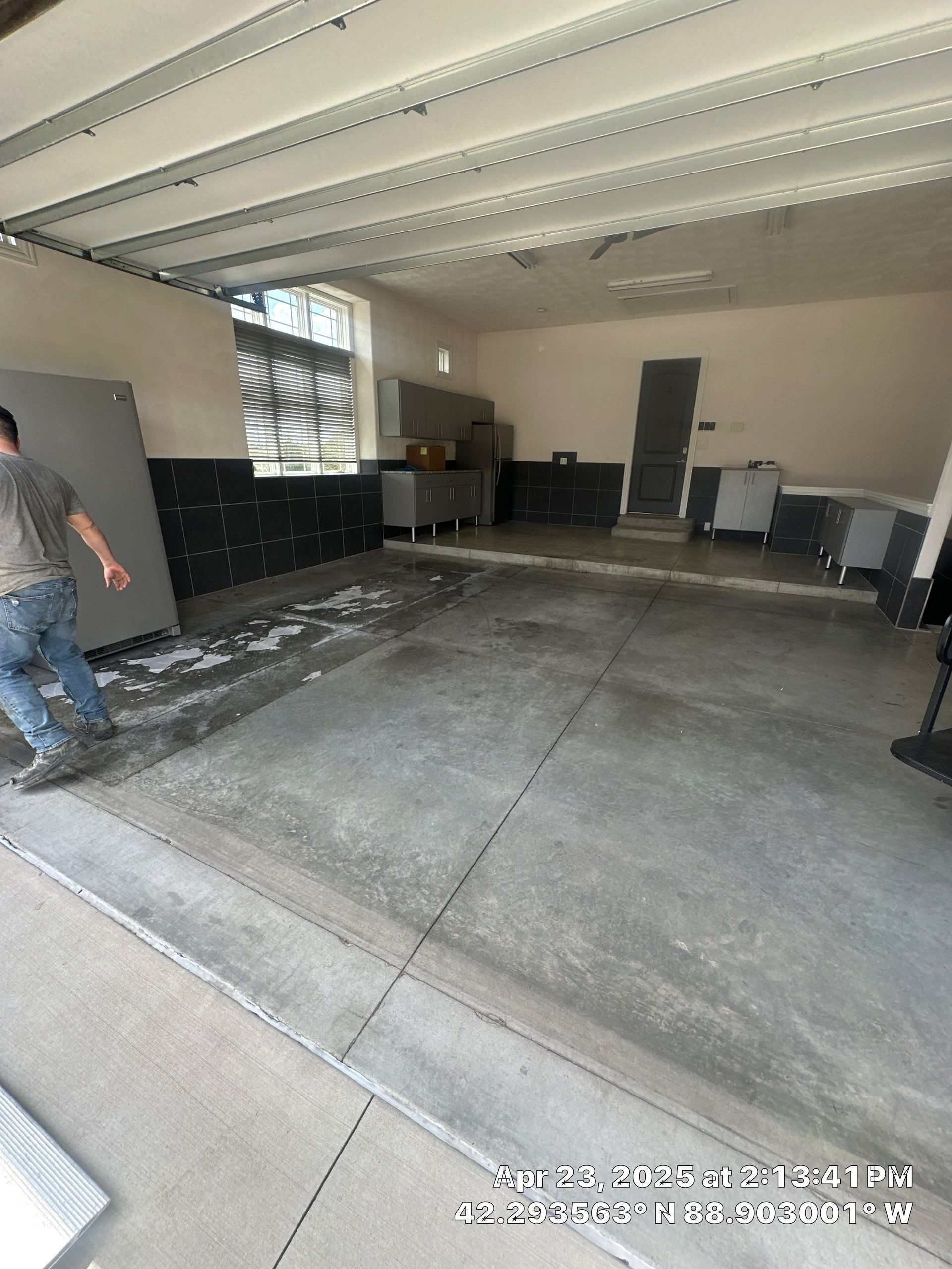 Empty concrete garage with cabinets and a person walking in from the left.