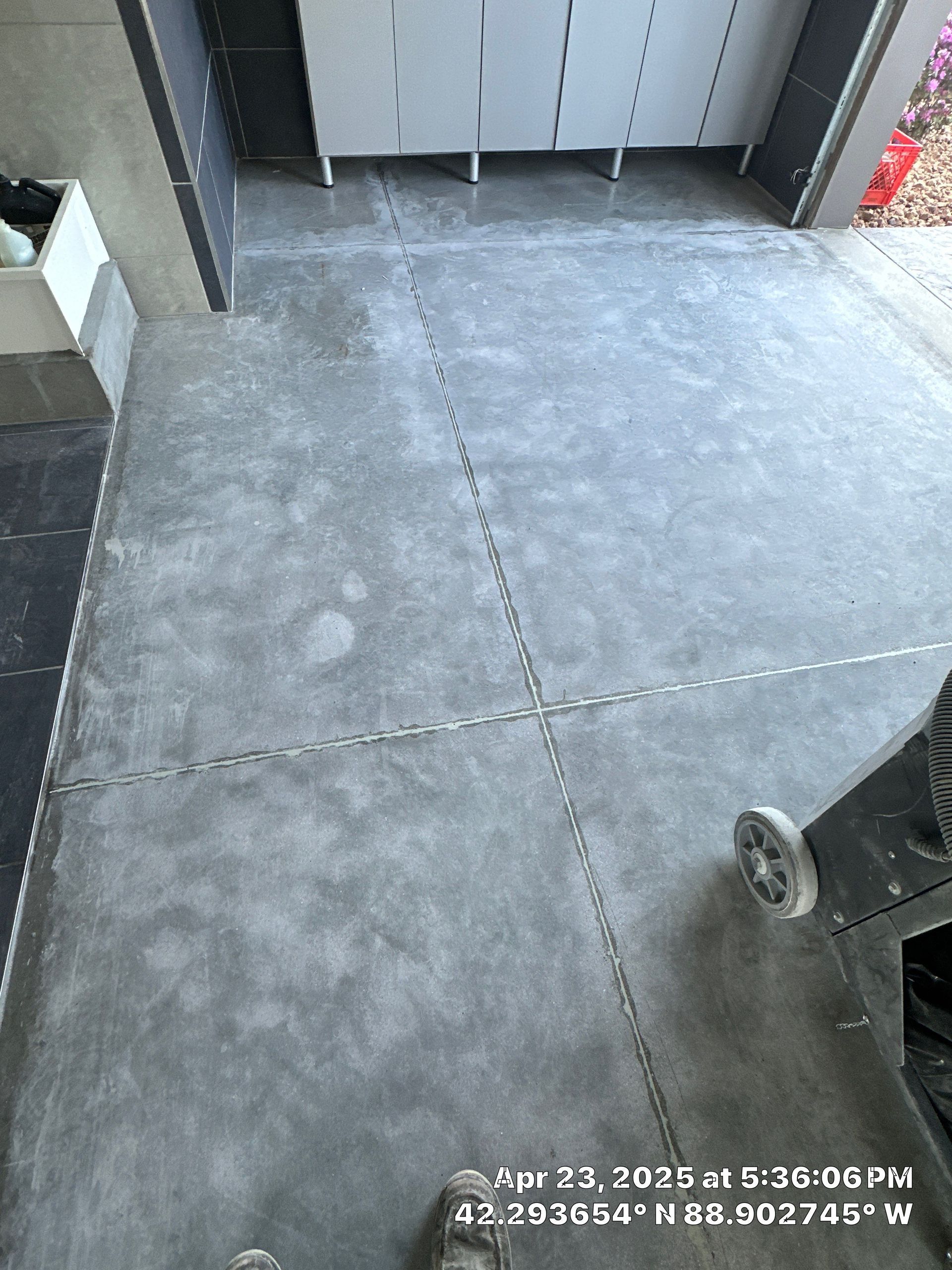 Empty concrete patio beside cabinets, with a wheeled cart at the right edge.