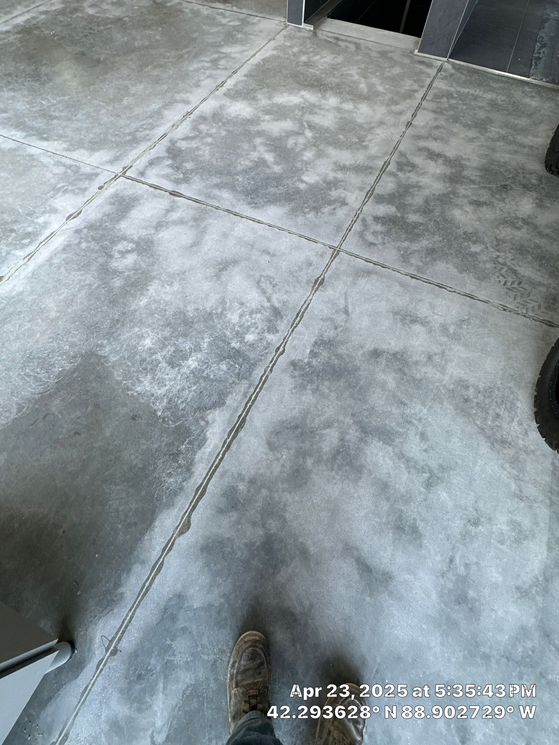 Gray concrete floor tiles with a person’s shoe at the bottom edge.
