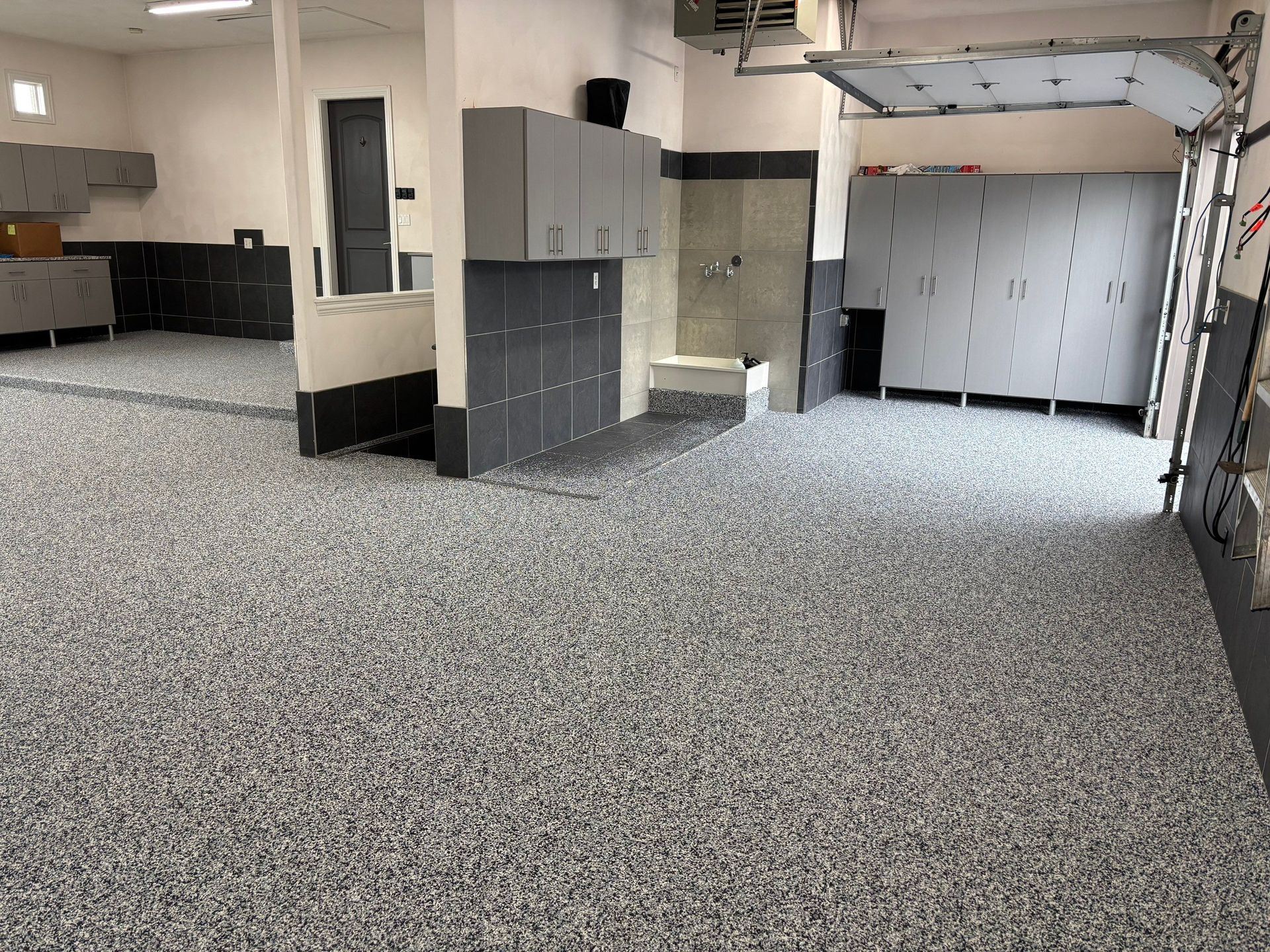 Empty garage or utility room with gray carpet, storage cabinets, and overhead track lighting.