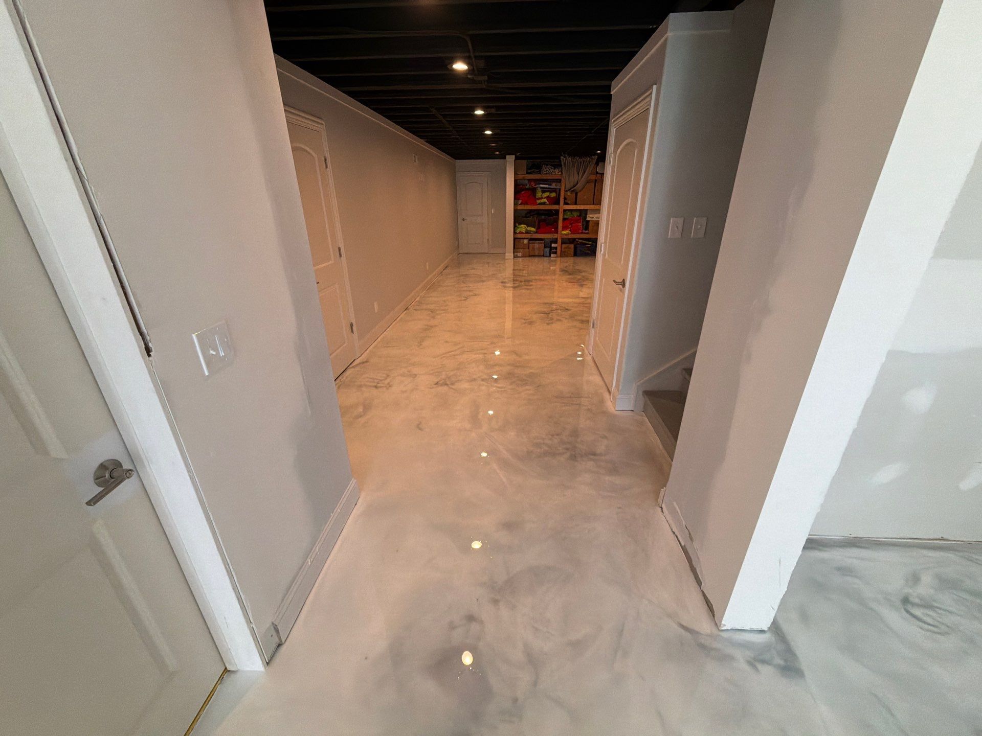 Empty hallway with white walls and glossy floor, leading to a darker space in the distance.