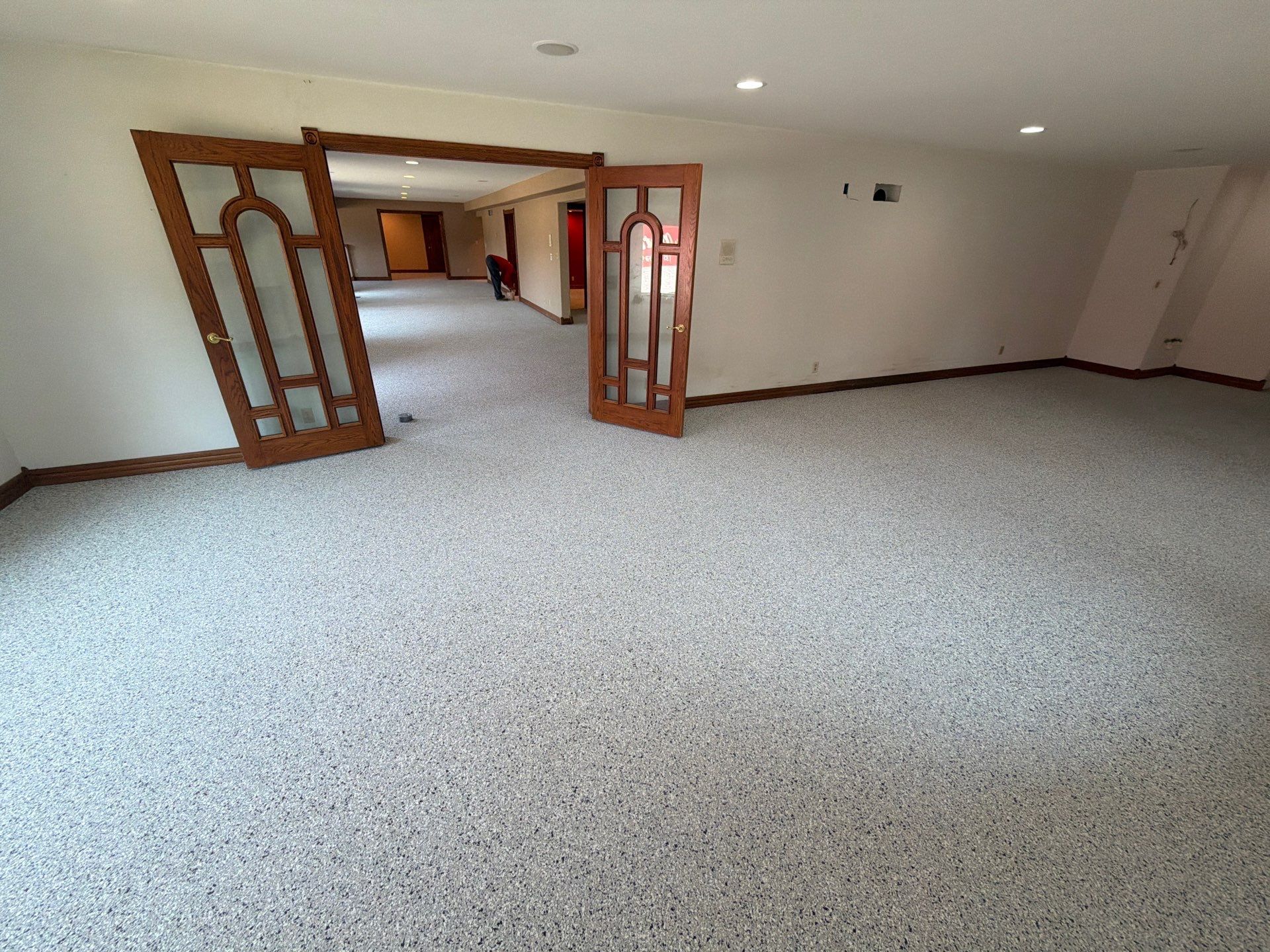 Empty carpeted room with open wooden doors and white walls