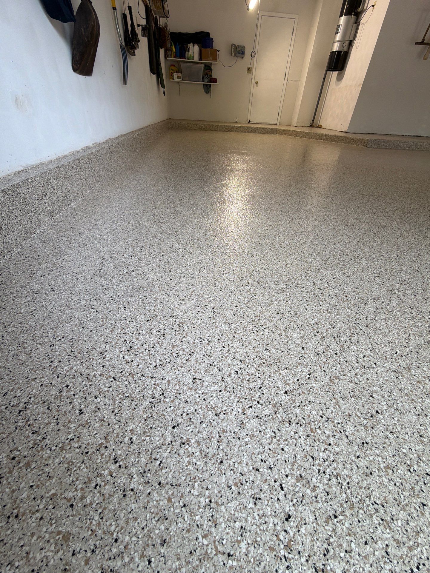 Speckled epoxy garage floor in a hallway with white walls and open doors