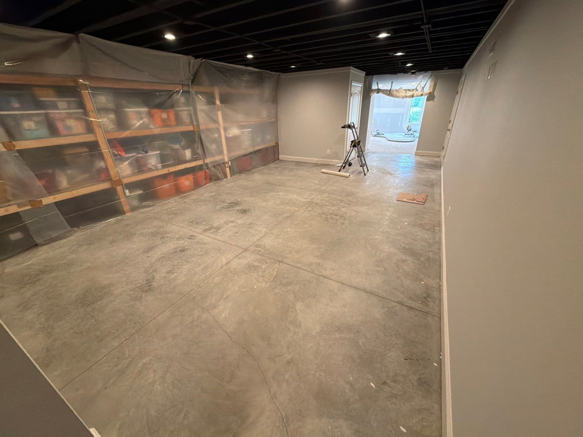Empty warehouse aisle with shelves on the left and an open doorway at the far end