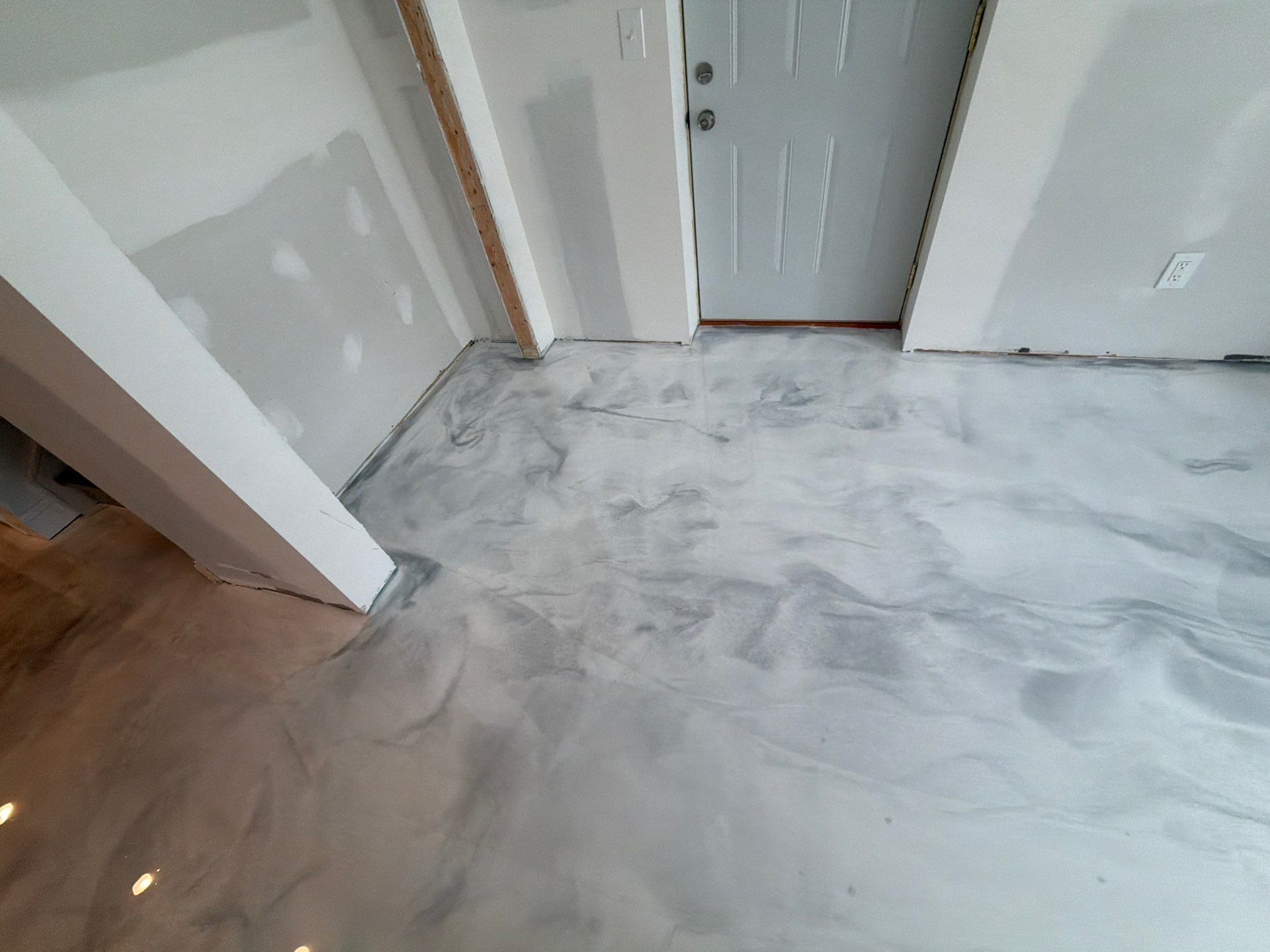 Empty hallway with unfinished concrete floor and white walls near a doorway
