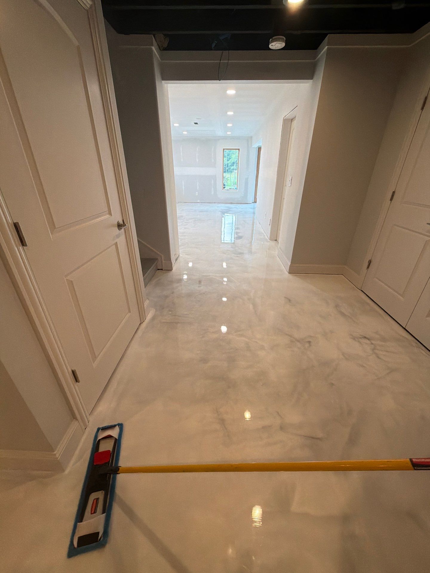 Bright hallway with glossy marble floor, white walls, and a level tool in the foreground.
