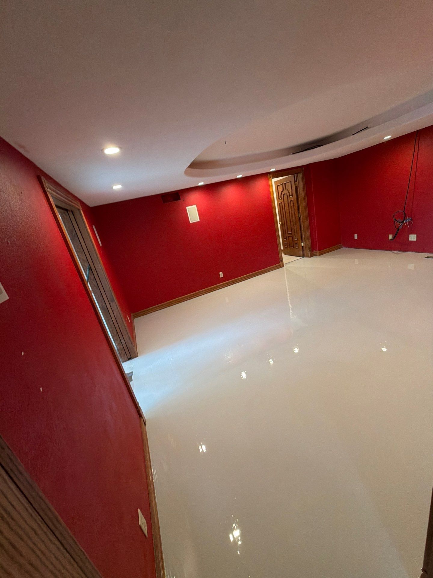 Empty red room with glossy white floor and recessed ceiling lights, shot at a tilted angle