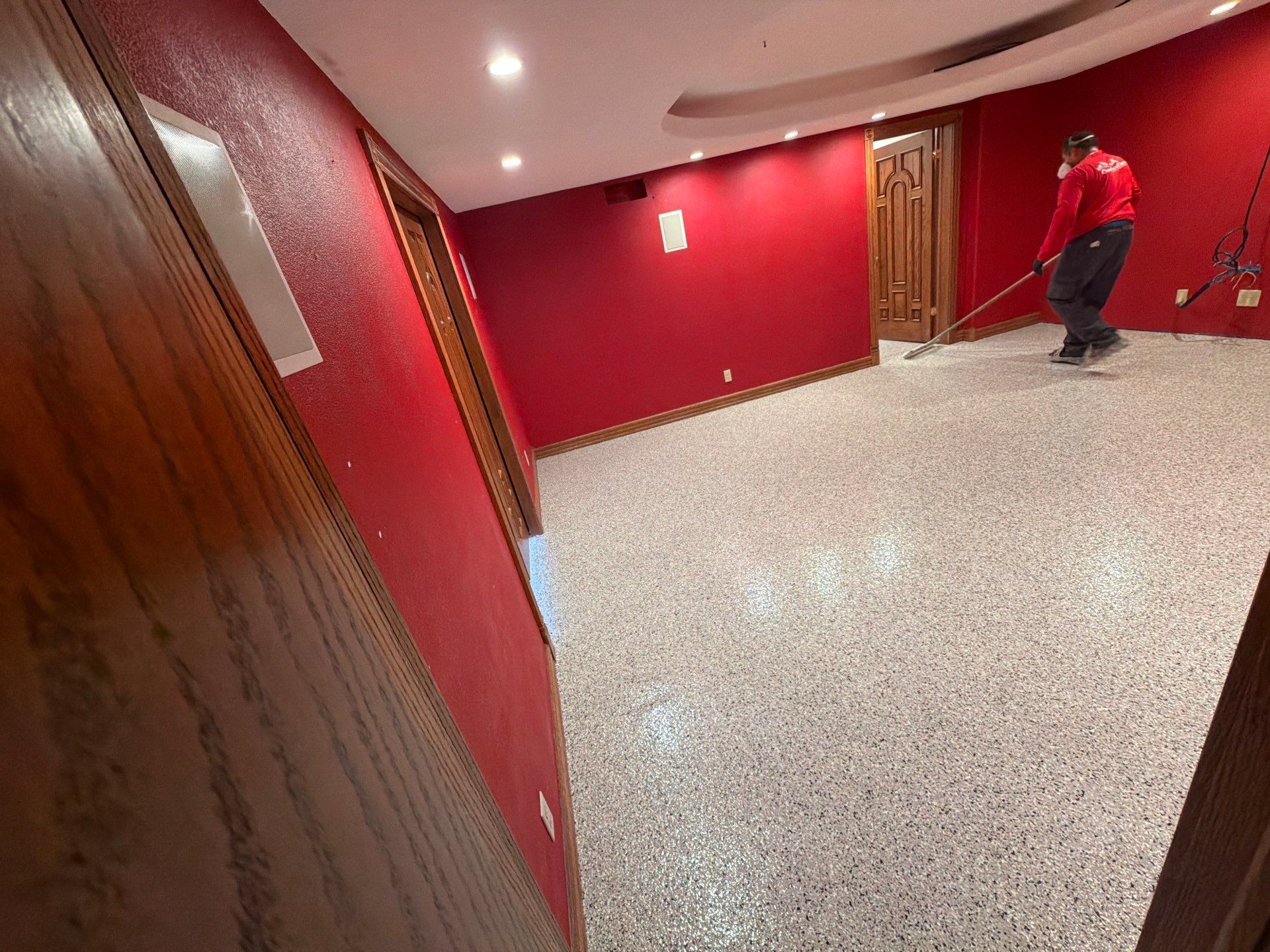 Red hallway with red walls, wood trim, and a person standing near the far door.