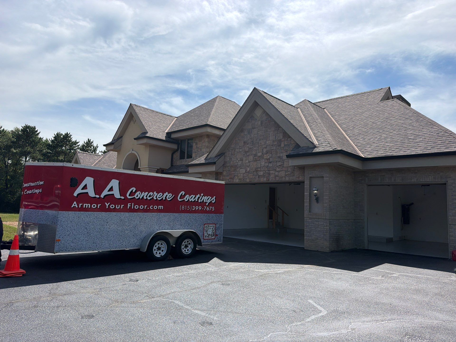 Red AA Carpet Cleaning trailer parked beside a tan house in a driveway under a sunny sky