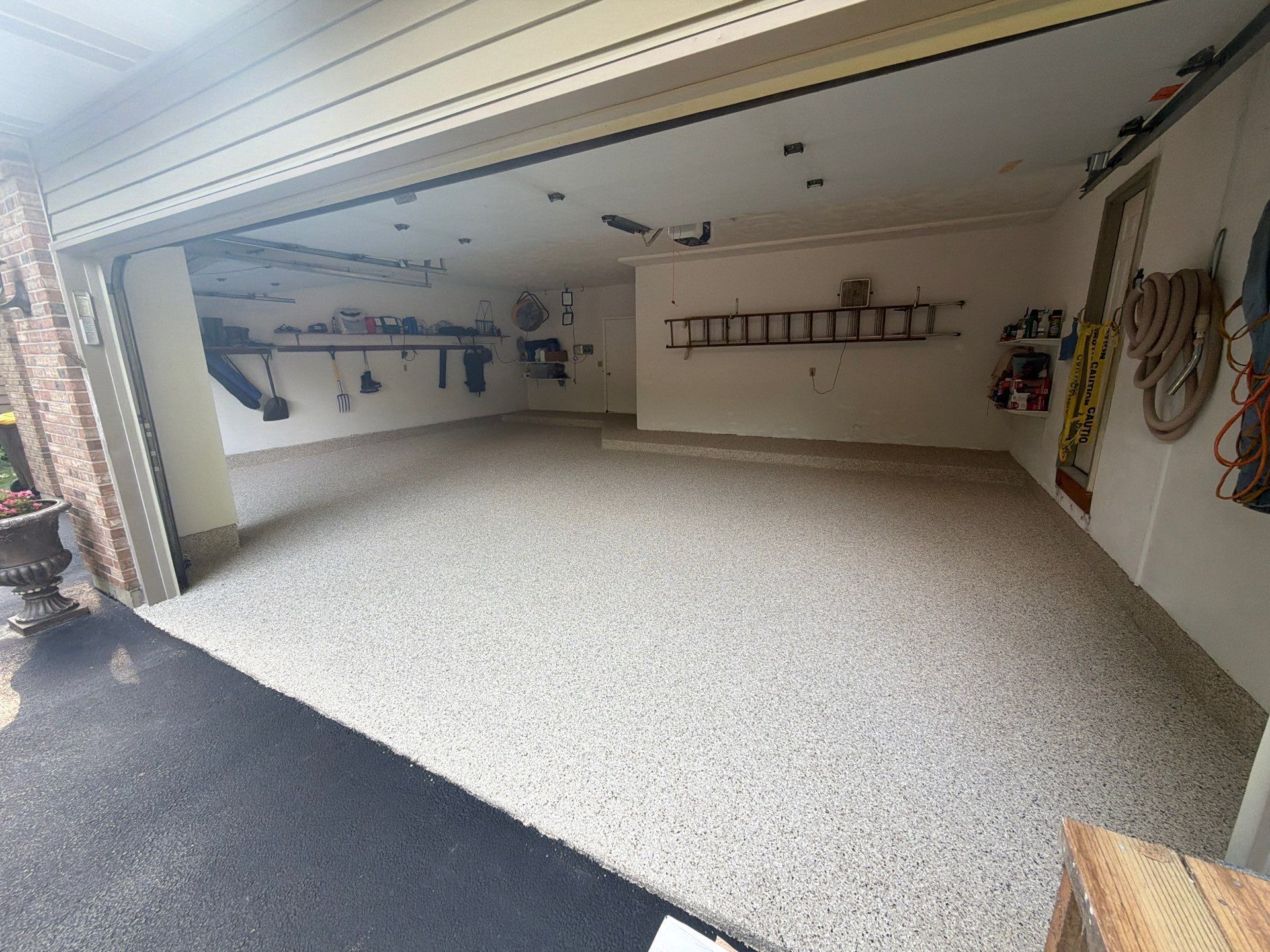 Spacious empty garage with open door, white walls, and a light-speckled floor